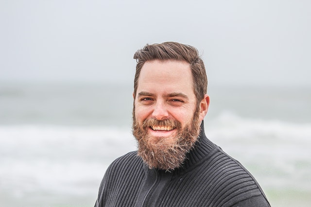 Usmiaty muž s dlhou bradou v čiernom svetri 